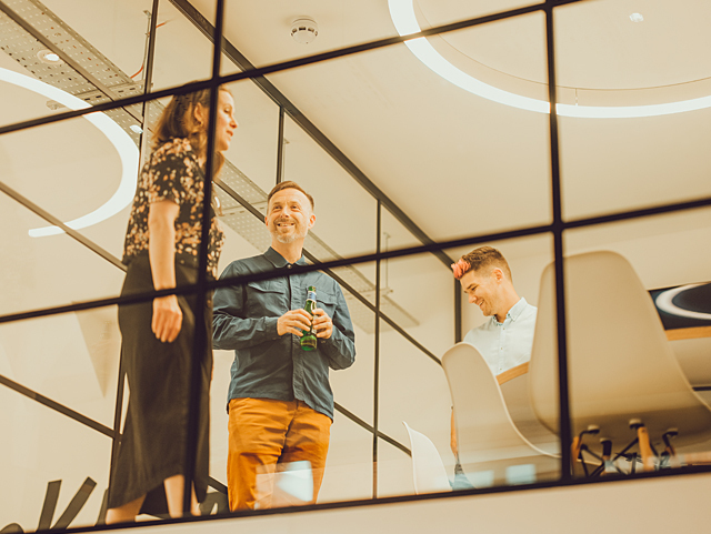 Two IE consultants chatting with a client in one of the agency's meeting rooms, overlooking the Birmingham studio