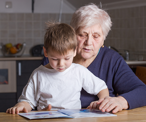 A woman reading a book with her grandson
