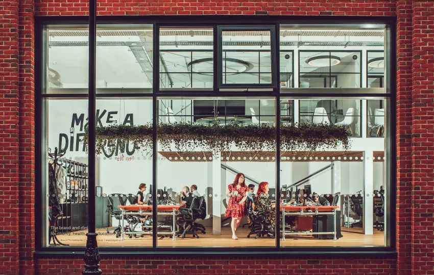 The IE studio in Birmingham viewed through the window, with the agency team hard at work, collaborating on brand and digital projects